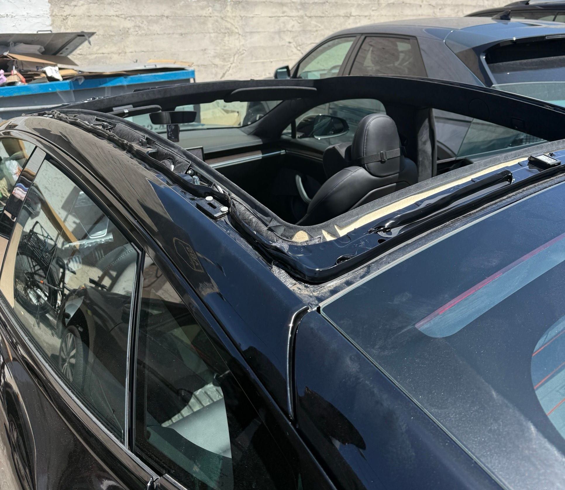 Black Tesla Model 3 with its roof glass removed during a replacement